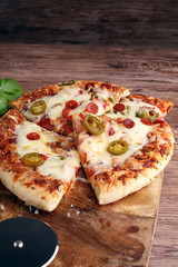 Hot pizza slice with melting cheese on a rustic wooden table. It