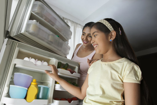 Close-up Of Daughter And Mother Looking In The Fridge 