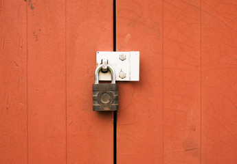 a metal padlock protecting locking two wooden doors outside - Powered by Adobe