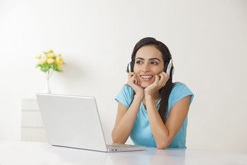 Relaxed woman with laptop listening to headphones at home