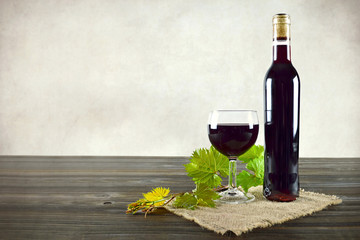 Red wine bottle and glass on wooden table, copy space