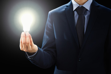 Concept, Hands of businessman holding illuminated light bulb sign.