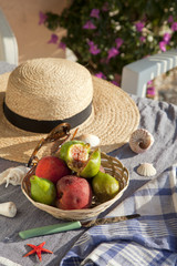 Still life with fruits, hat and sea shells in the sunlight