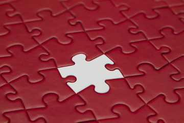 Red jigsaw puzzle and one piece white.  