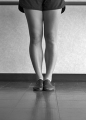 Black and white version of legs of a jazz dancer in first position at the barre in jazz class
