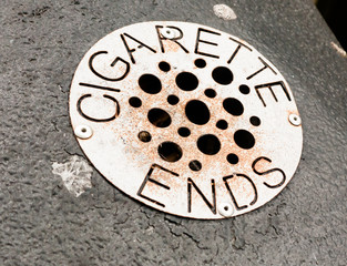 close up of metal grate with holes on bin for cigarette ends