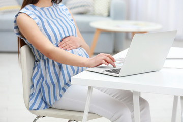 Beautiful young pregnant woman working at home