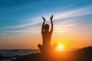 Yoga silhouette. Fitness and healthy lifestyle. Meditation woman on the ocean during amazing sunset.