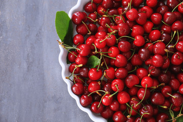 Plate with fresh ripe cherries on grey background
