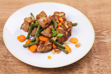 Sauteed liver with vegetables on white plate