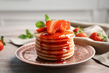 Plate with delicious pancakes on table