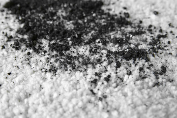 Scattered soil on white carpet, close up