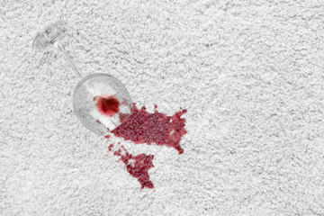 Glass of red wine spilled on white carpet