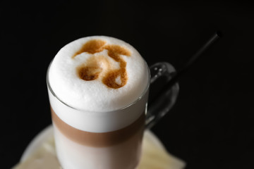 Hot coffee latte in tall glass on black background