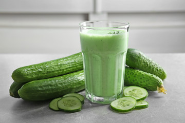 Glass of fresh smoothie and cucumbers on table