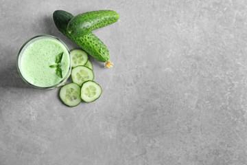 Glass of fresh smoothie and cucumbers on table