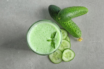 Glass of fresh smoothie and cucumbers on table