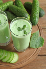 Composition with fresh smoothie and cucumbers on wooden background