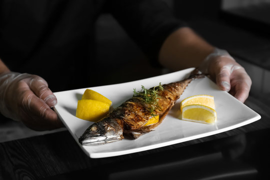 Male hands holding plate with tasty fish