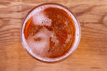 Glass of beer on wooden background. View from above, top studio shot