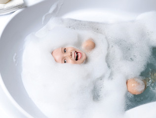 Happy little baby girl face swimming in the bathroom