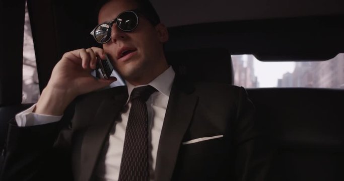 Businessmen on phones in backseat of car, slow motion
