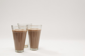 Two glasses of chai with an empty glass isolated over white background 