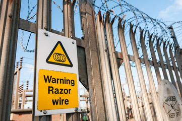 Warning sign on a fence warning of the existance of razor wire.