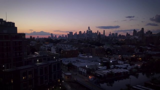evening descending tilting up shot of Manhattan skyline revealing roof top water tank in Brooklyn