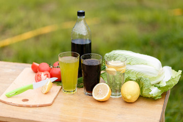 With a knife cut a lemon on a wooden Board background with fresh vegetables and summer lemonade and a wood Desk. Sliced lemons and a knife on a cutting Board.