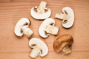 Mix of whole and sliced brown champignon mushrooms on a breadboard