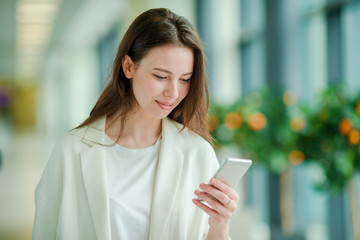 Portrait of young woman with smartphone in international airport. Airline passenger in an airport lounge waiting for flight aircraft