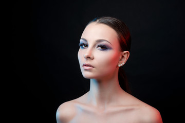 Close-up portrait of young brunette woman with clean skin and bright makeup on black  isolated background