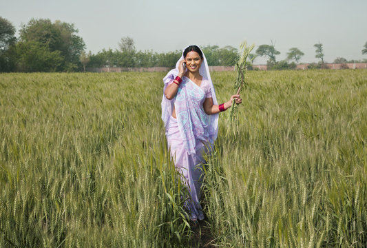 Portrait of an Indian female worker talking on phone while walking in the field 