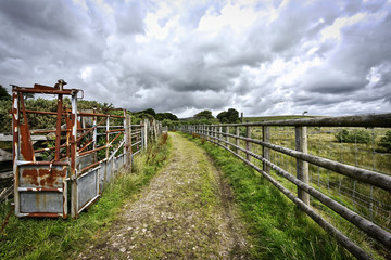 Wooden fence by a footpath on grassy fields in the green countryside in England UK