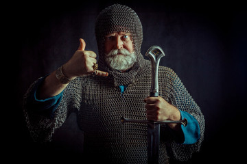 Powerful bearded knight with the sword on the dark background