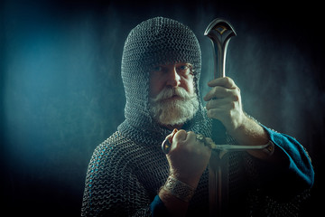Powerful bearded knight with the sword on the dark background