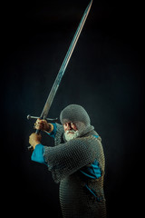 Powerful bearded knight with the sword on the dark background