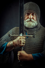 Powerful bearded knight with the sword on the dark background