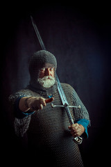 Powerful bearded knight with the sword on the dark background