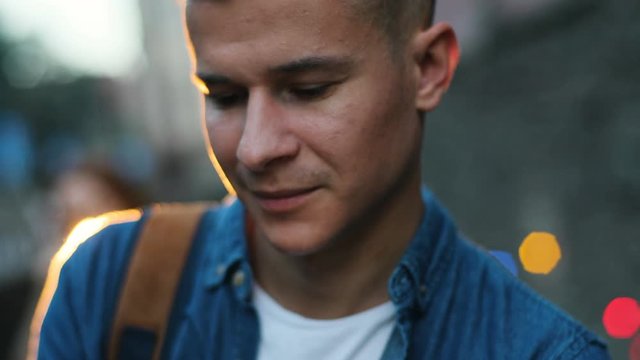 Portrait of young stylish man in the city centre at the evening time during sunset with bokeh. Close up shot.