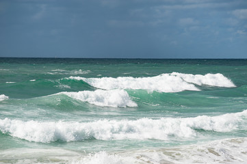 Crushing waves, white puffy clouds, blue sly  