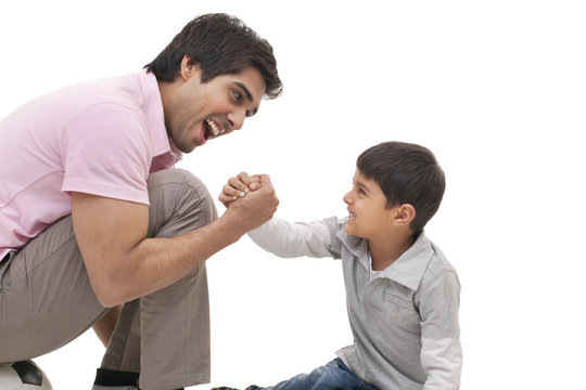 Young man arm wrestling with his son over white background 