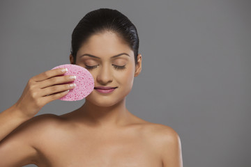 Close-up of woman using massage sponge on her face 