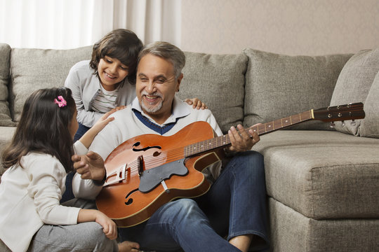 Grandfather Playing Guitar For Grandchildren At Home