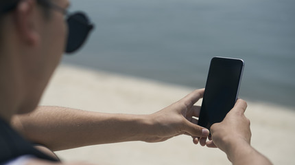 A man works for a smartphone on the beach