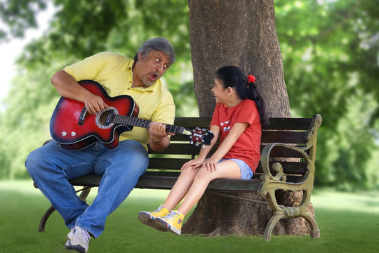 Grandfather playing the guitar for granddaughter 