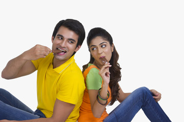 Young Indian couple enjoying ice-cream bars over white background