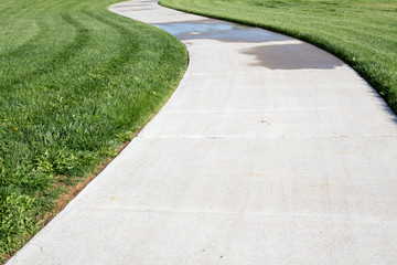 Curving concrete sidewalk through green grass