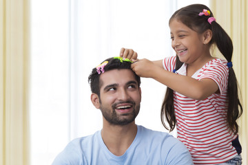 Daughter placing clips in fathers hair and making funny hair style